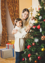 Fototapeta na wymiar Portrait of mother decorating Christmas tree with daughter