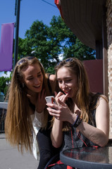 Two girlfriends are using cellphone 