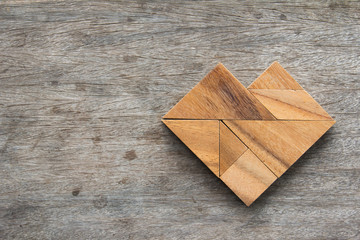 Tangram puzzle in heart shape on wooden table