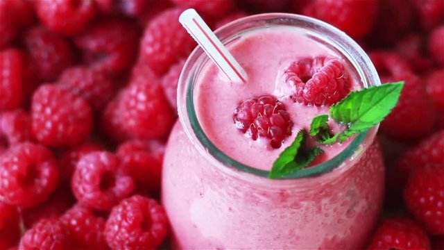 Beautiful appetizer pink raspberries fruit smoothie. Yogurt cocktail. Close up. Natural detox. Liquid ice cream. Glass of raspberry milk shake with berries background 