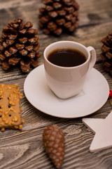 Small white cup of coffee, cocoa beans, hazelnuts, cookies, cone, christmas decoration on wooden background