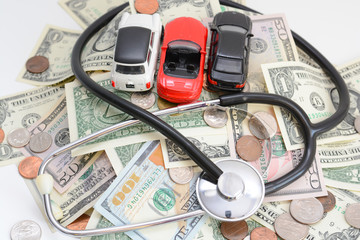 Automotive industry analyses concept with toy cars and stethoscope on money