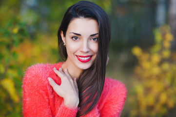 Naklejka premium Portrait of a beautiful young woman with red lipstick on autumn background