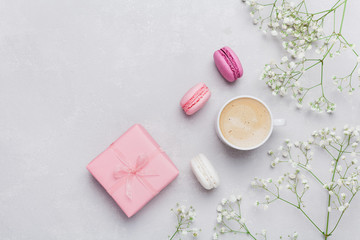 Morning cup of coffee, cake macaron, gift or present box and flower on light table from above. Beautiful breakfast. Flat lay style.