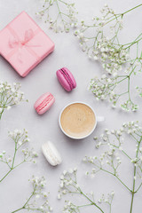 Morning cup of coffee, cake macaron, gift or present box and flower on gray table from above. Beautiful breakfast. Flat lay style.