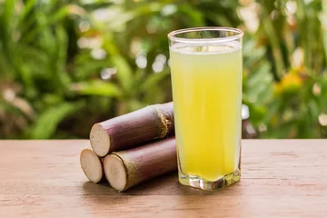 Photo sur Plexiglas Jus Sugarcane juice with piece of sugarcane on wooden background