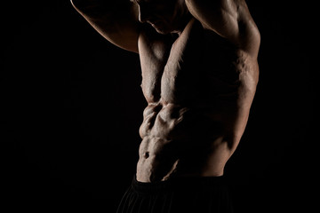 Obraz na płótnie Canvas torso of attractive male body builder on black background.