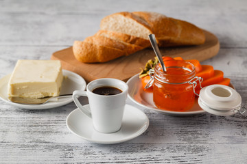 Ripe persimmons with jam in glass saucer and cinnamon on table o
