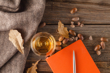 Cup of coffee with an old book and oak leaves. On wooden backgro