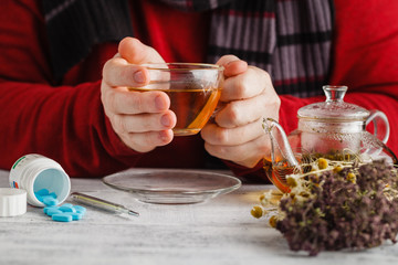 Hot tea against fever. Male looks the temperature on the thermom