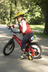 Fototapeta premium Young boy riding his first bicycle with training wheels 