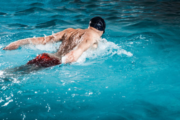Young healthy man with muscular body swims