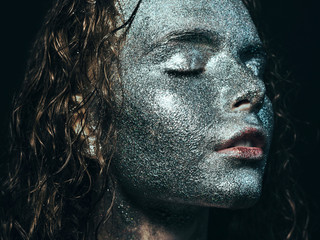 Girl in glitter Girl in glitter on her face with wet curly hair on black background Close-up
