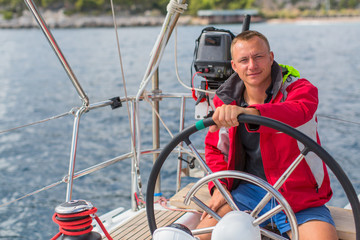 Man skipper steers boat sailing yacht on the sea.