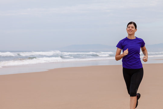 Female athlete running at the beach on an Autumn day.