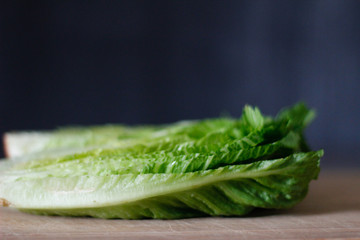 Fresh Romaine lettuce hearts on a bamboo cutting board with a dark background