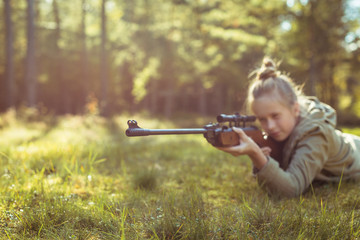 Fototapeta premium Girl shooting from the air rifle in the forest