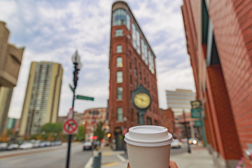 cup of coffee on a background of Boston. triangular Flatiron Building. walking around historic downtown Boston with coffee in hand. the concept of sightseeing, tourism and traveling. 