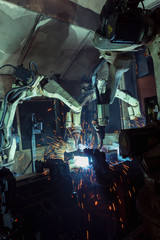Team robots welding automotive part in assembly line