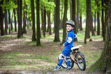 Happy kid boy of 4 years having fun in autumn or summer forest with a bicycle