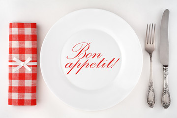 Bon appetit! Poster with a vintage cutlery, plate and a checkered napkin on a white background