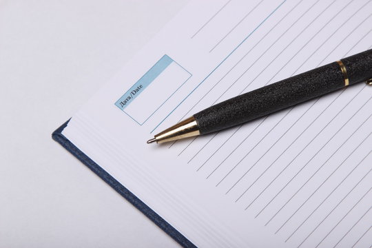 black ballpoint pen lying on a notebook