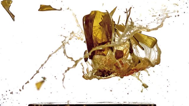 Bottle of Beer falling, Breaking and Splashing on Steel Plate against White Background, Slow motion