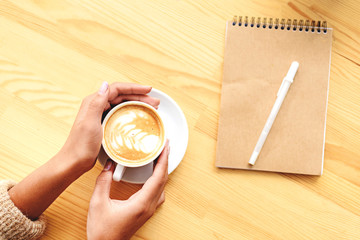 top view of hands with latte and notepad
