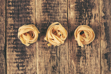 raw homemade italian tagliatelle on wood surface