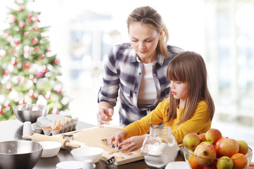 Christmas timePortrait of happy mother and her cute daughter baking together at home in christmas time. 