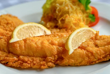 Fotobehang Fish dish - fried cod fish with lemon and sauerkraut. © vivoo