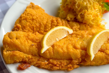 Delicious fried cod fish with lemon and sauerkraut.