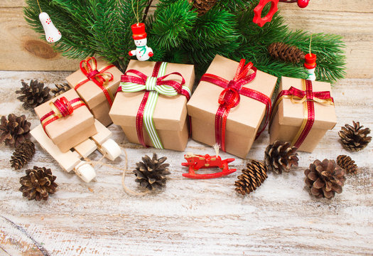 Christmas or New Year background: fur-tree, branches, gifts, colored glass balls, decoration and cones on wooden background