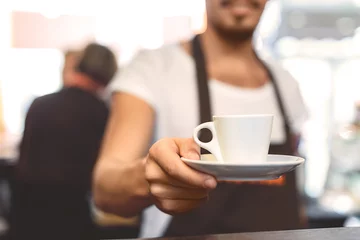 Zelfklevend Fotobehang blurred barista holding mug with beverage © Yakobchuk Olena