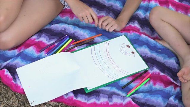 Mother and son paint a rainbow on a sheet of paper. Mother with her son are drawing pictures in the park