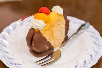Chocolate cream puff with peach and cherry topping