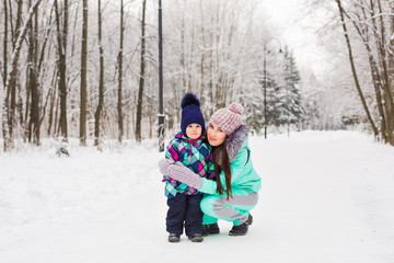 Fototapeta na wymiar happy mother and baby in winter park. family outdoors. cheerful mommy with her child