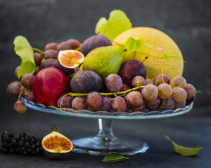 Fresh grapes and figs and other fruits on stone background. Autumn fruits still life.