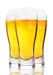 Glasses of cold beer with foam and froth on white