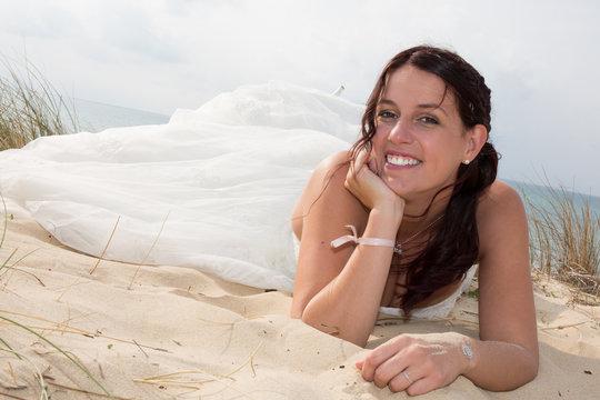 Pensive bride lying on the sand in the sea