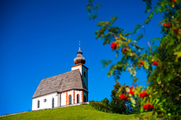 Fototapeta na wymiar Beautiful little church in Alps. Sunny day, green grass on the h