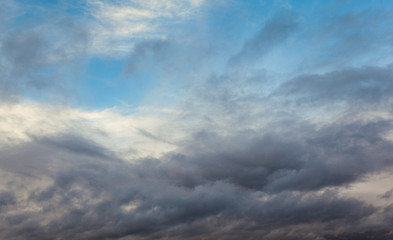 Obraz premium Beautiful dramatic sky with gray clouds and sunset. Dark blue feather shaped clouds in the background of bright orange sunset.