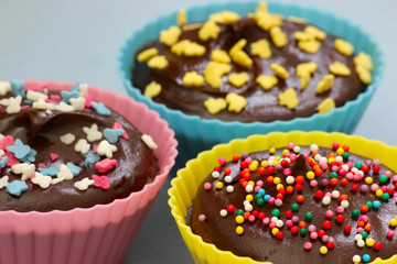 Close up of sweet homemade chocolate cupcakes with frosting on top with sugar sprinkles. Selective focus. 
