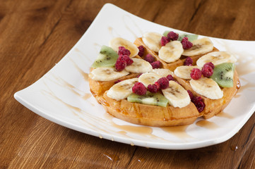 Wafer cake in a square white plate on a wooden lacquered surface with reflection