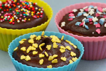 Close up of sweet homemade chocolate cupcakes with frosting on top with sugar sprinkles. Selective focus. 