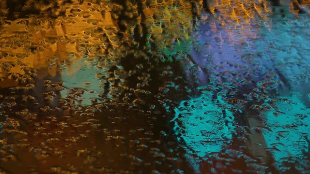 blur background. Moving bokeh circles of night traffic. Defocused night traffic lights Through the glass in drops of rain Thailand. Moving particles. Colorful, blurred, bokeh lights background