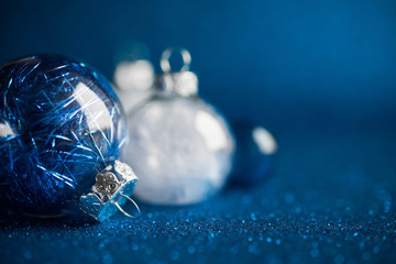 White and silver christmas ornaments on dark blue glitter background. Merry xmas card. Winter holidays.