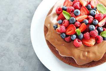 Homemade chocolate cake with berries on grey wooden table