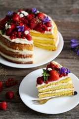 Delicious biscuit cake with berries on grey wooden table
