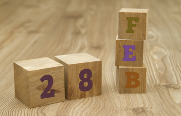 Cube shape calendar for February 28 on wooden surface.